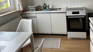 A modern kitchen with white cabinetry, a built-in oven, and a window with curtains.