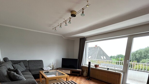 Uma sala de estar moderna com um sofá seccional, uma mesa de centro e uma TV de tela plana.