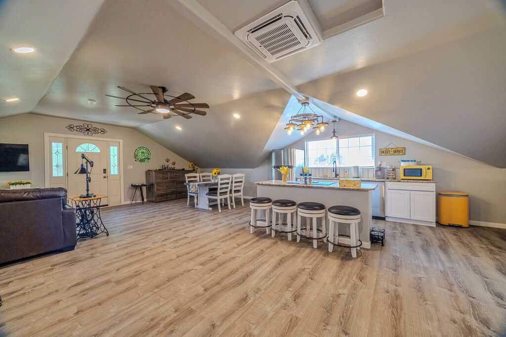 Un loft spacieux avec un plafond haut, un coin cuisine doté de tabourets de bar et une table à manger.