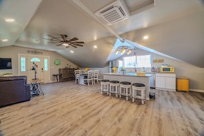 A spacious loft with a high ceiling, a kitchen area with bar stools, and a dining table.