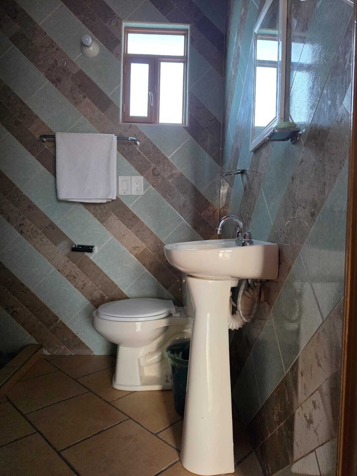 Un baño con inodoro, lavabo y ventana.