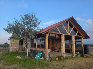 A rustic cabin with a sloped roof, wooden beams, and a glass enclosure.