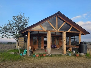 Una cabaña rústica con un amplio ventanal, vigas de madera y un porche.