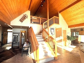 A spacious interior with a wooden staircase, a dining area, and a kitchen. - Sunrise Ridge|Great Views,Hot Tub, +Pets, 10 Acres (Angel Fire)