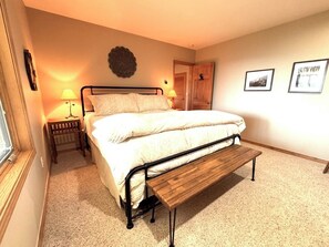A bedroom with a bed, bedside lamps, a bench, and framed pictures on the wall. - Sunrise Ridge|Great Views,Hot Tub, +Pets, 10 Acres (Angel Fire)