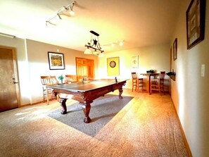 A pool table in a room with a carpeted floor, a chandelier, and framed pictures on the walls. - Sunrise Ridge|Great Views,Hot Tub, +Pets, 10 Acres (Angel Fire)