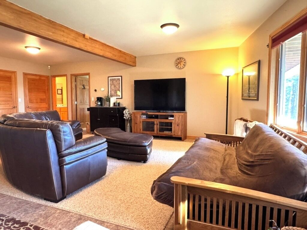 A living room with a sofa, ottoman, and a television.