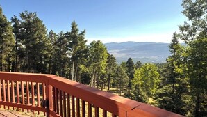 Um deck de madeira com vista para uma floresta e montanhas ao longe.