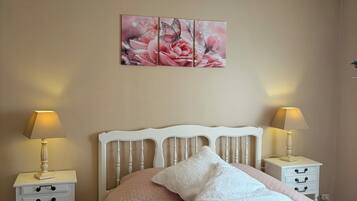 A bedroom with a bed, two bedside tables, a wall-mounted lamp, and a decorative wall piece.