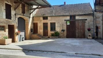 Un patio con un edificio de piedra, una puerta de madera y un área empedrada.