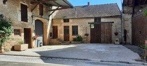 A courtyard with a stone building, a wooden door, and a paved area. - Gîte Ô détour d'un Souvenir
Venez créer vos propres Souvenirs ! (Planay)