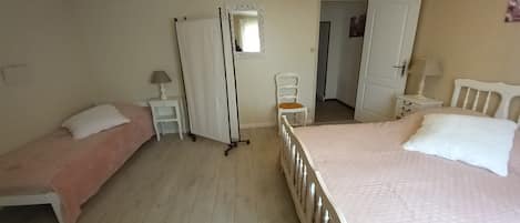 A bedroom with two single beds, a chair, a wardrobe, and a mirror.