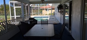 Eine überdachte Terrasse mit Pool, Sitzgelegenheiten im Freien und Blick auf eine Wohngegend.