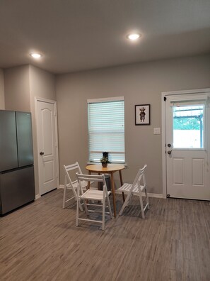 A kitchen with a refrigerator, a dining table with chairs, and a window with blinds. - Cozy 3BR home in the Woodlands. Perfect for families! (Tomball)