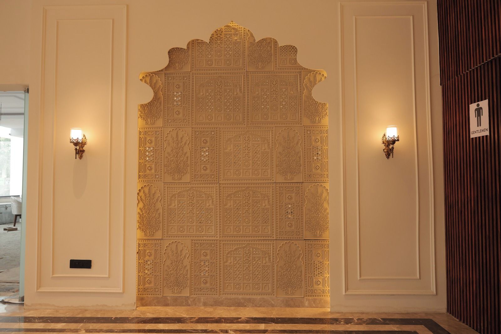 Una pared con intrincados grabados y dos lámparas de pared.