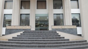 Un bâtiment avec un escalier en pierre menant à une entrée constituée d’une porte en verre.