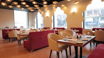Interior de restaurante con cabinas, mesas y lámparas colgantes.