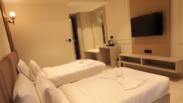 Ein Hotelzimmer mit zwei Betten, einem Fernseher, einem Schreibtisch und einem Spiegel.