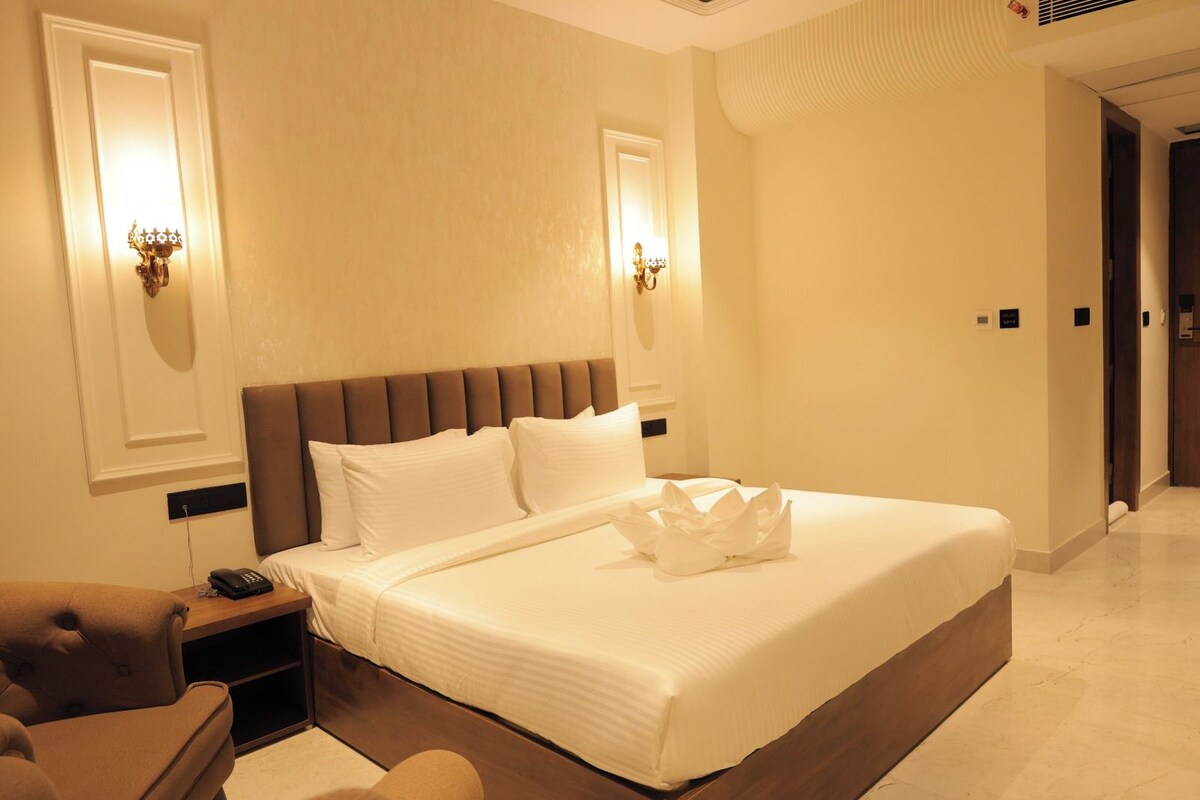 A hotel room with a large bed, bedside lamps, a nightstand, and a chair.
