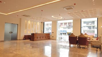 A spacious lobby with a reception desk, seating area, and large windows offering views of the outside.