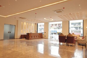A spacious lobby with a reception desk, seating area, and large windows offering views of the outside.