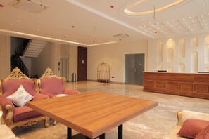 Un hall amplio con una recepción, una escalera y un área de descanso con sofás decorados.