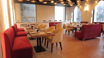 A restaurant with red upholstered booths, yellow chairs, and a long communal table.