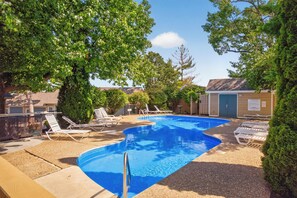 Ein Pool mit Liegestühlen, umgeben von Bäumen und einem kleinen Gebäude.