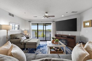 Uma sala de estar com sofá, mesa de centro, TV e varanda com vista.