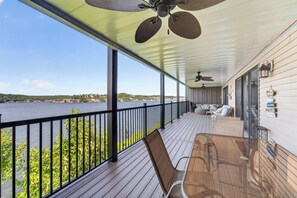 Eine überdachte Terrasse mit Seeblick, einem Tisch mit Stühlen und einem Deckenventilator.