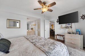 Quarto com cama, ventoinha no teto, televisão e cômoda.