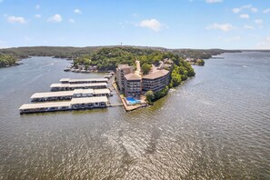 A waterfront property with a dock, a swimming pool, and a building with multiple floors. - Lake views! 3 Bdrm 3 Bath Falls condo (Lake Ozark)