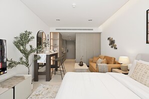 A modern bedroom with a bed, a desk, a sofa, and a dining area. - Bloomfields Studio in NAS3 - Arjan  (Dubai)