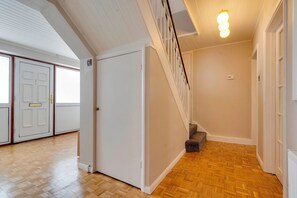 A hallway with wooden flooring, white walls, and a staircase with a light fixture above. - Spacious Home near Addenbrookes with Free Parking - Pass the Keys (Cambridge)