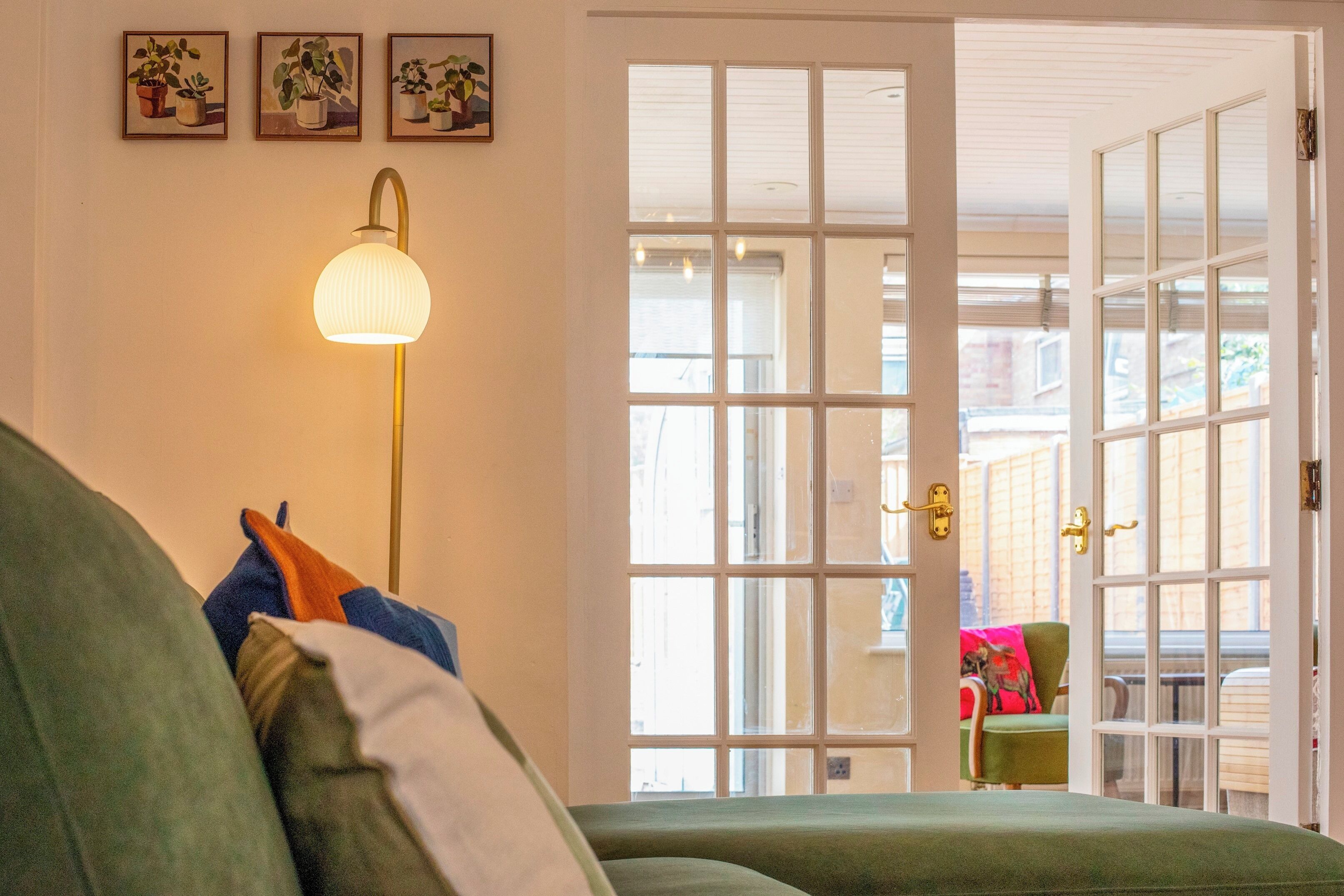 Ein Zimmer mit einem grünen Sofa, einer Stehlampe und einer Tür zu einem Außenbereich.