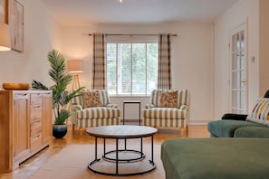 A cozy living room with striped armchairs, a round coffee table, a green sofa, and a wooden cabinet. - Spacious Home near Addenbrookes with Free Parking - Pass the Keys (Cambridge)