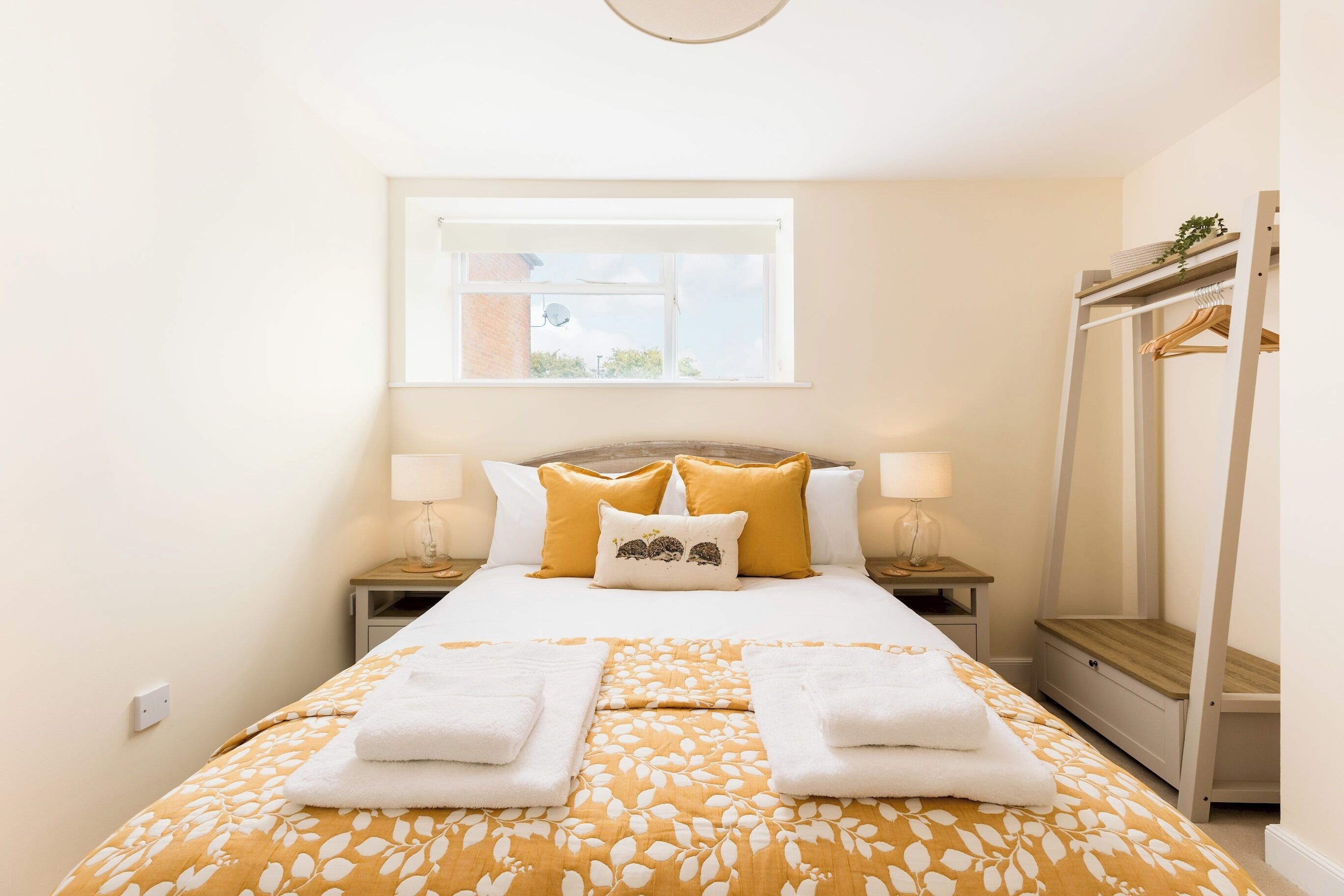 A hotel room with a bed, two bedside tables, a window, and a wardrobe.