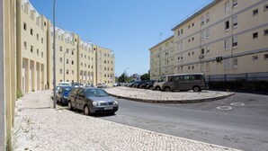 A parking area with multiple cars, a cobblestone path, and a row of buildings with balconies. - Lisbon Olivais Residence – 2BR Apartment (Lisbon)