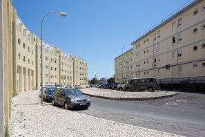 A parking area with multiple cars, a cobblestone path, and a row of buildings with balconies. - Lisbon Olivais Residence – 2BR Apartment (Lisbon)