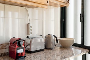 Eine Küche mit Toaster, Wasserkocher und einem roten Gerät auf der Arbeitsfläche.