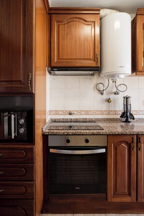 A kitchen with wooden cabinets, a Bosch water heater, a dishwasher, and a granite countertop. - Lisbon Olivais Residence – 2BR Apartment (Lisbon)