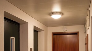 A hallway with a wooden door, a black door, and a light fixture on the ceiling. - Lisbon Olivais Residence – 2BR Apartment (Lisbon)