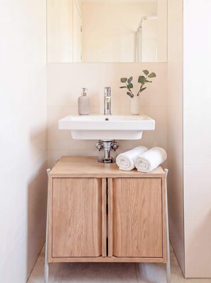 A bathroom with a white sink, a mirror above it, and a wooden cabinet below. - TurnKey | Elegant Studio for 2 | Republic Square (Hlavní město Praha)