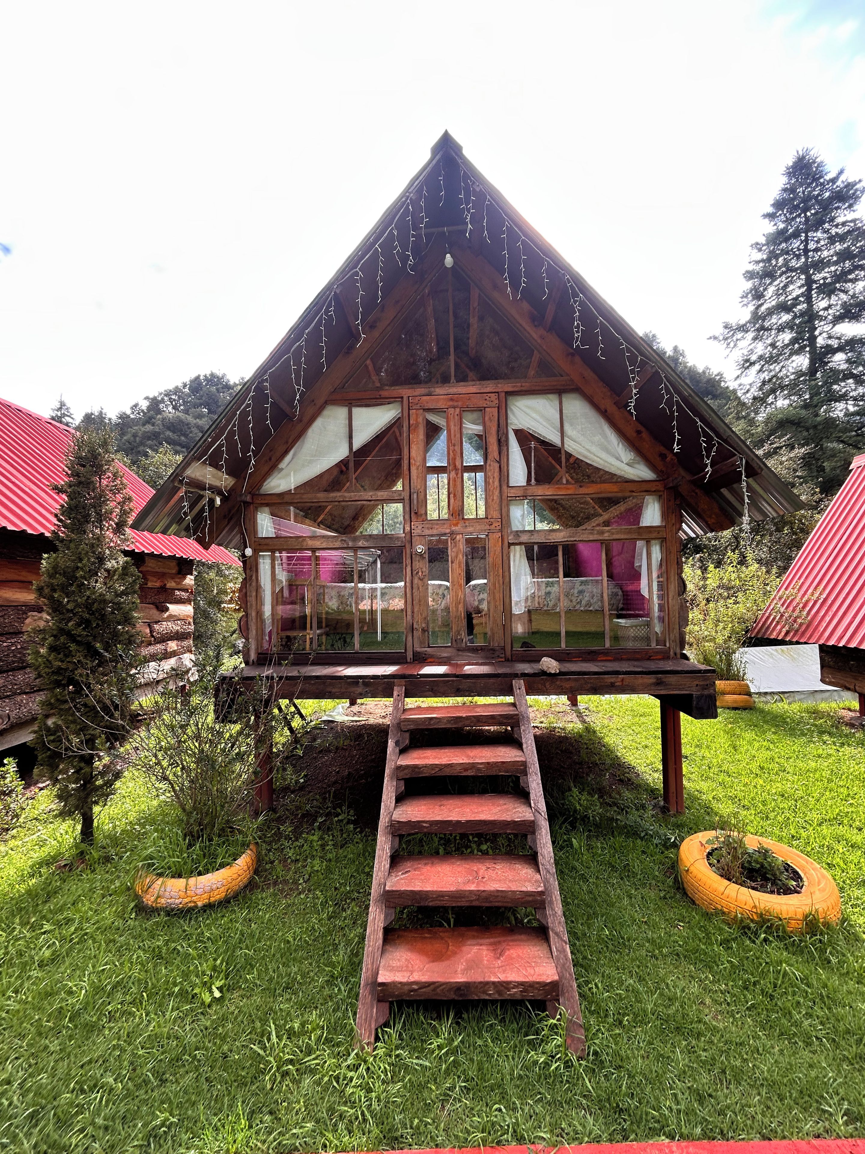 Eine Holzhütte mit einem Balkon, umgeben von Gras und Bäumen.