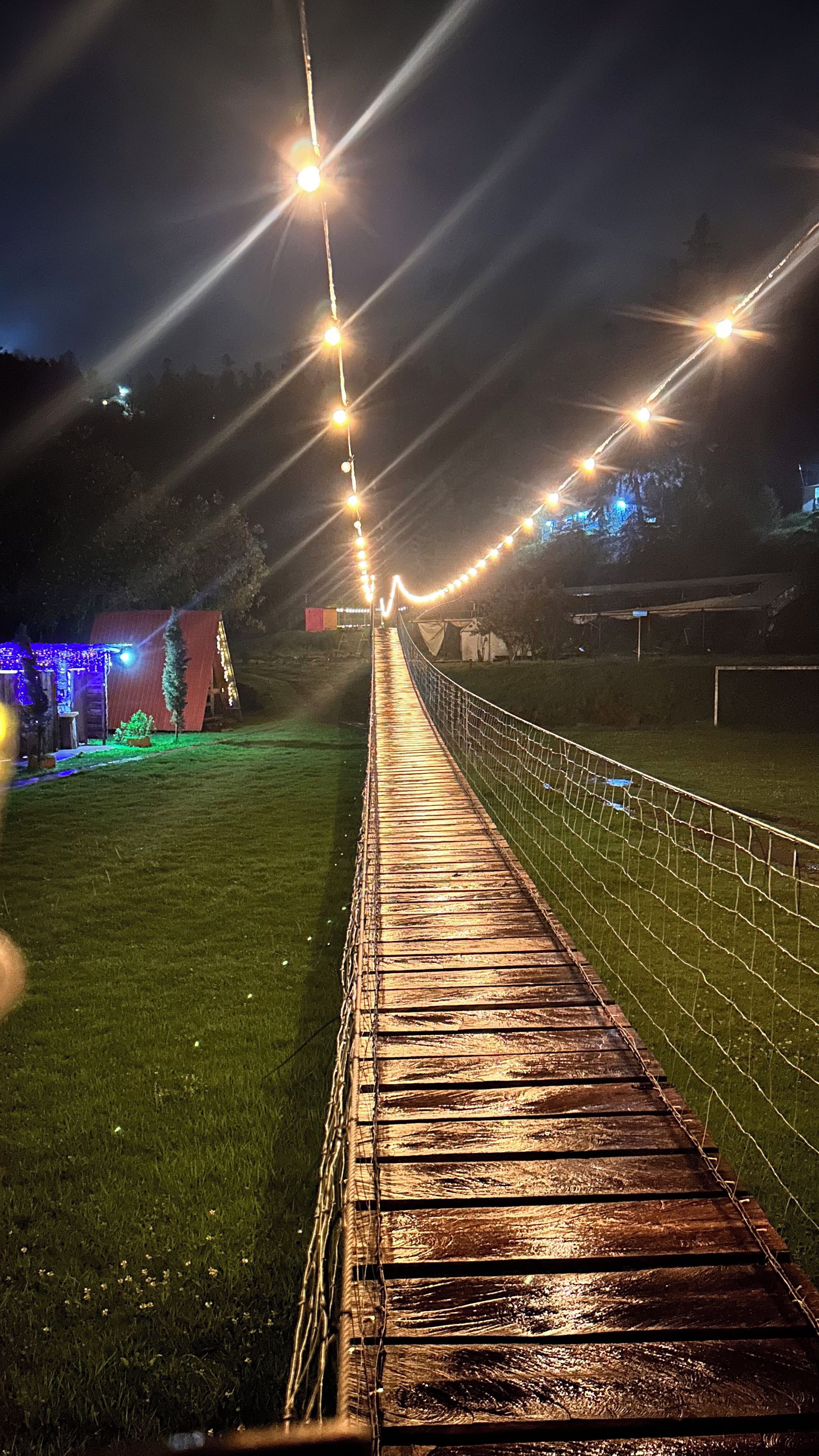 Un sendero de madera con luces de cuerda que conduce a un edificio con tejado rojo.