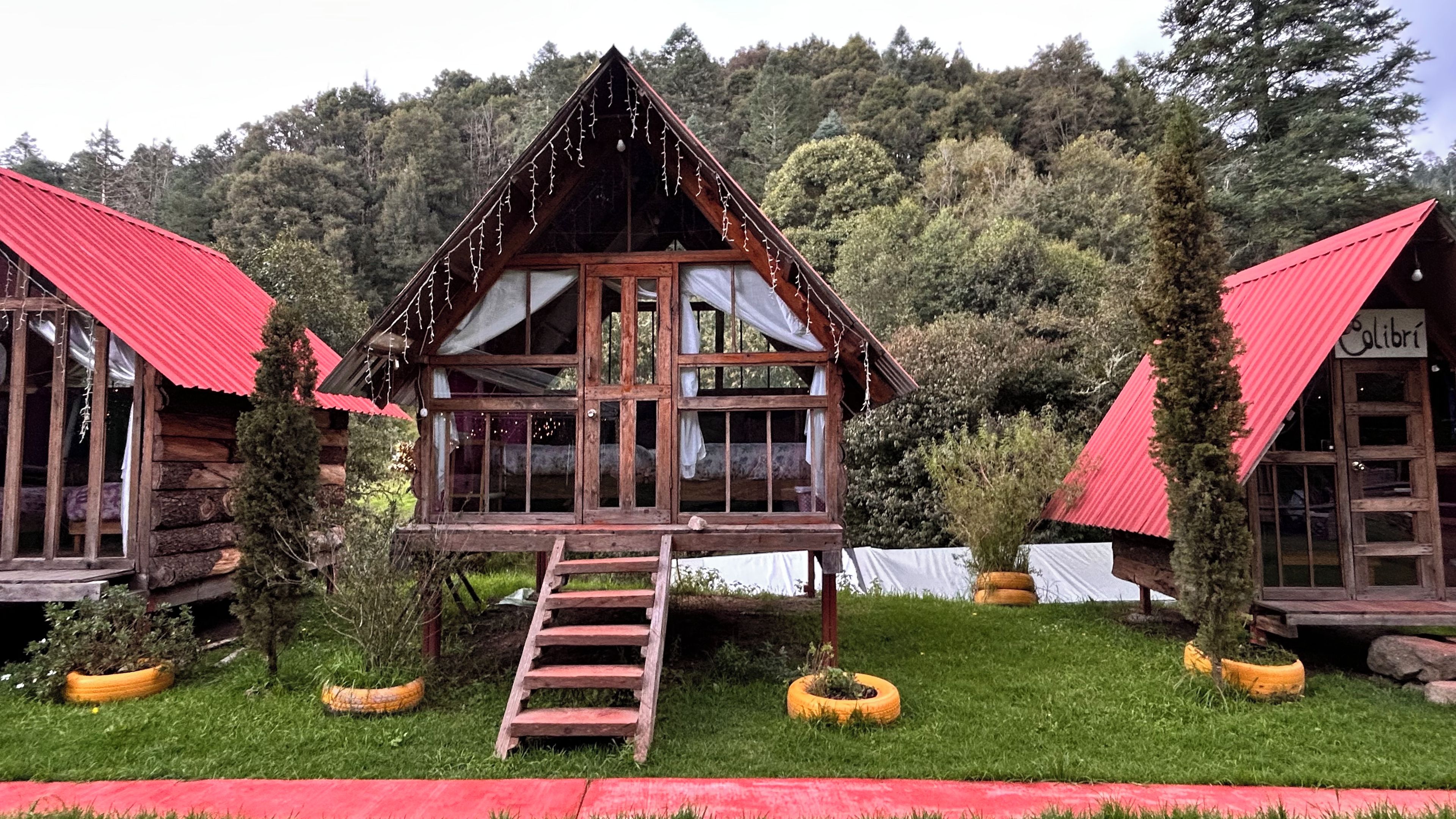 Eine Holzhütte mit rotem Dach, einer Leiter zum Eingang und einer kleinen Veranda.
