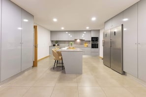A modern kitchen with a central island, built-in appliances, and a dining area.