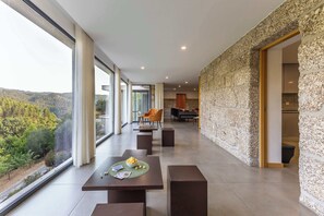 A modern interior with a dining area, a stone accent wall, and a view of the outdoors.