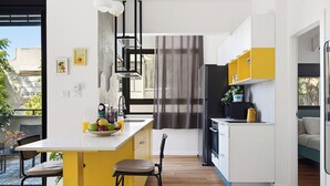 Een moderne keuken met een centraal kookeiland, barstoelen, een koelkast en een magnetron.