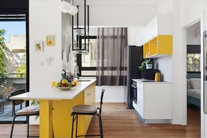 A modern kitchen with a central island, bar stools, a refrigerator, and a microwave. - Modern City Apt Near Talpiot Market (Haifa)